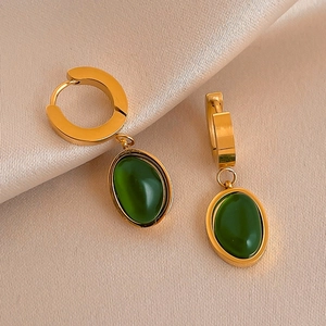 Détail de boucles d'oreilles ovales en résine vert émeraude sur soie champagne élégante