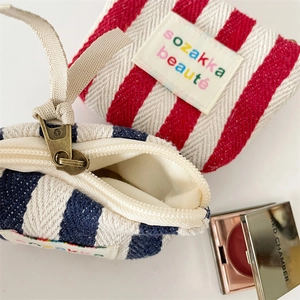 Close-up of striped canvas makeup bags with vintage zippers and textile logo labels
