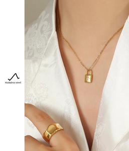 Detail showing 18k gold plated stainless steel padlock necklace and wide band ring set