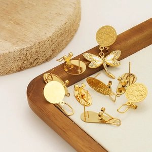 Golden round drop earrings set with heart patterns and dragonfly detail on wooden tray