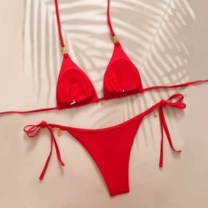 Detail of red halter bikini set featuring metallic star charms and side-tie bottom