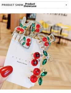 Close-up of sparkling cherry rhinestone hair clips with red crystals and gold alloy base