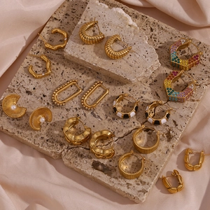 Collection of vintage 18K gold-plated titanium steel earrings on a beige stone surface
