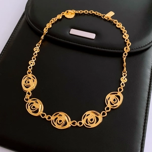Detail of golden rose hollow flower necklace on a premium black leather background