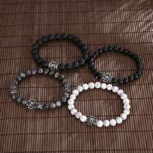 Detail of four matte black agate and turquoise beaded bracelets with skull cross charms