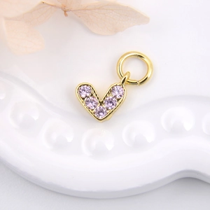 Macro shot of a gold heart charm with light purple zircon for DIY jewelry making
