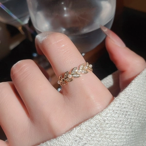 Close-up of golden leaf ring with zircon stones and tiny pearls on a model hand
