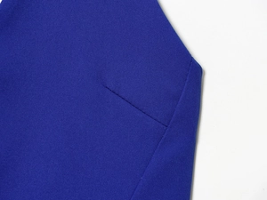 Vue macro du tissu bleu foncé de la robe montrant la texture fine et les détails de couture