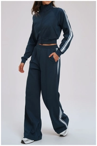 Detail view of contrast white three-stripes on dark navy sports tracksuit pants