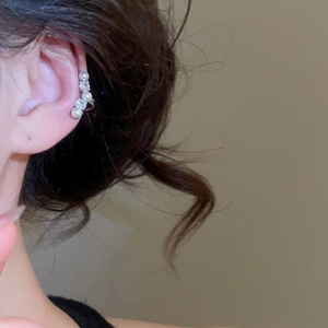 Gros plan d'un ear cuff élégant avec perles et zircons porté par un mannequin