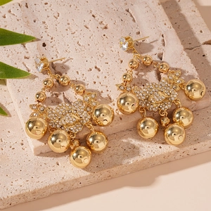 Détail de boucles d'oreilles fleur dorées avec clous en zircon et sphères pendantes
