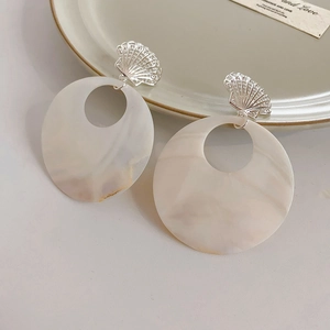 Detail of marble-textured resin earrings with starfish shells and silver round rings