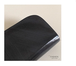 Dettaglio di una borsa in pelle nera alla moda con finitura lucida e bordi arrotondati