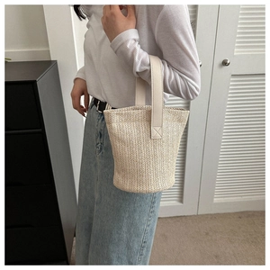 Detail of hand-woven bucket bag with stylish leather handles in off-white finish