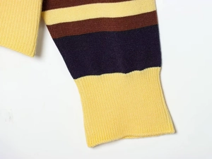 Macro view of striped knit sleeve with yellow ribbed cuffs and fine textile texture