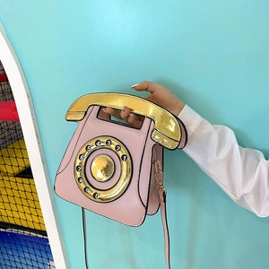 Detail view of pink vintage telephone bag showing the gold handset handle and dial