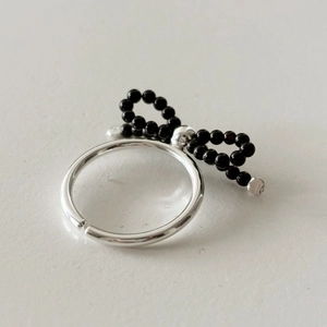 Detail of a 925 silver bow ring featuring black beads and an adjustable open band
