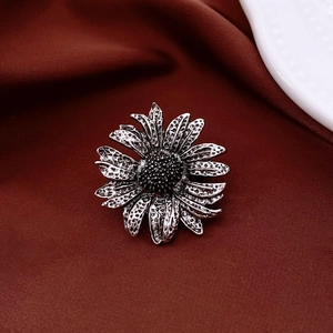 Macro shot of vintage daisy flower brooch with crystal details on brown velvet background