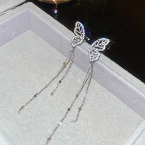 Macro detail of silver butterfly earrings with hollow zirconia wings and chain tassels