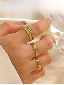 Macro detail of three-piece gold stainless steel geometric rings on silk fabric