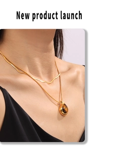 Close-up of double layer gold necklace featuring teardrop tiger eye stone pendant on model