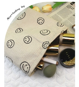 Detailed view of cream corduroy makeup bag with smiley face and cosmetic tools