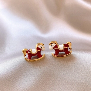 Vue rapprochée des boucles d'oreilles cheval à bascule en émail rouge sur satin