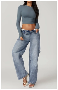 Detailed view of slim fit yoga top with thumbholes and distressed wide-leg denim jeans