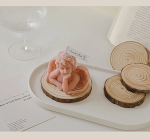 Pink angel-shaped candle with 'Save the Date' flag on a decorative wooden tray setup