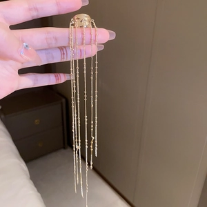 Detail of gold tassel finger ring with multiple hanging metal chains and bead accents
