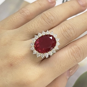Macro shot of oval red ruby ring with a halo of white zircons on a silver band