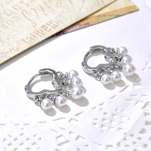Elegant heart-shaped hoop earrings with dangling white pearls on vintage background