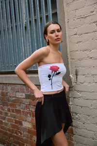 Detail of white cropped tube top featuring a vibrant red rose print and slim fit style