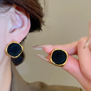Detail of vintage gold-trimmed black flocked square earrings worn for elegant styling