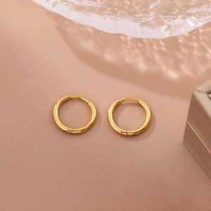 Macro detail of polished 18K gold stainless steel hoop earrings with secure closure