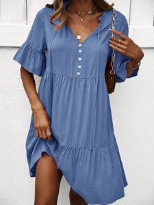 Détail d'une robe bleue à col en V avec boutons à l'avant et manches à volants