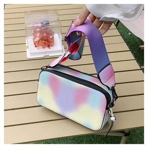Detail of colorful gradient camera bag with wide strap on an outdoor table
