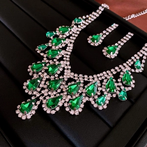 Detailed set of green teardrop pendant necklace and matching earrings on black velvet