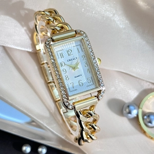 Macro detail of rectangle gold watch with diamond bezel on champagne silk background
