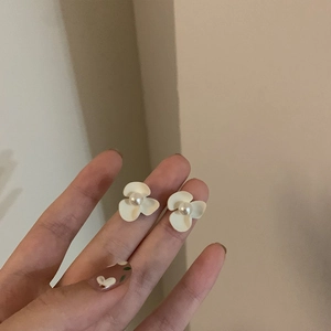 Vue rapprochée des boucles d'oreilles fleurs avec pétales blancs et détail de perle