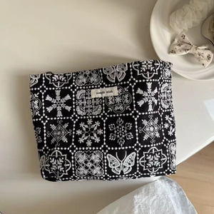 Detailed close-up of vintage floral embroidery on a black canvas cosmetics bag with label