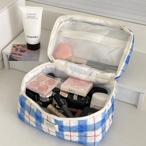 Close-up of quilted plaid makeup bag showing inner mesh pocket and zipper detail