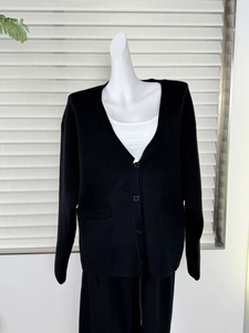 Detail of black V-neck knitted cardigan showing button closure and front square pockets