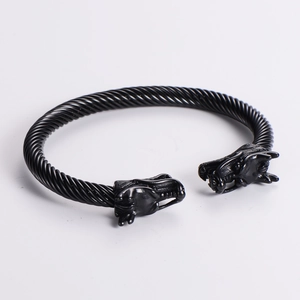 Detail of black twisted cable metal bracelet featuring antique dragon head motifs