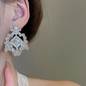 Détail de boucles d'oreilles baroques avec cristaux carrés et ronds sur un modèle