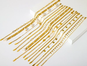 Gros plan de chevillières en acier doré avec perles et breloques étoiles sur fond blanc