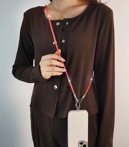Detail view of a sparkling red rhinestone crossbody phone lanyard on a white case