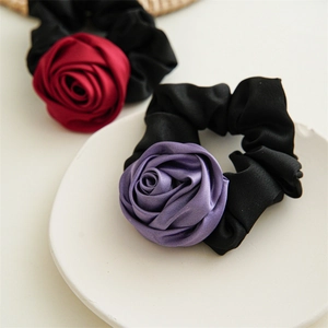Detail of satin rose flower hair scrunchies in red and purple on a white ceramic plate