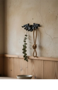 Detalle de gancho de murciélago en hierro fundido negro sobre pared retro con decoración natural