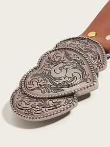 Detail of silver double heart-shaped metal buckle with floral engraving on brown leather belt